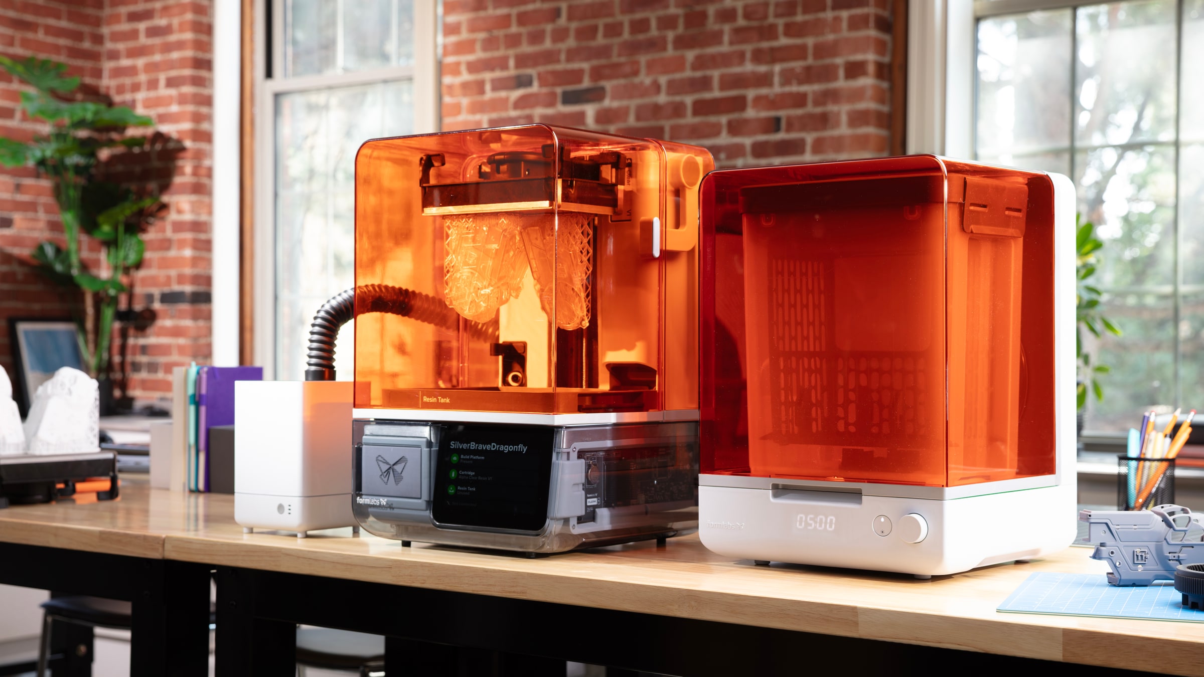 明亮工作室桌面上的 Formlabs 打印与后处理设备，带橙色透明上盖
